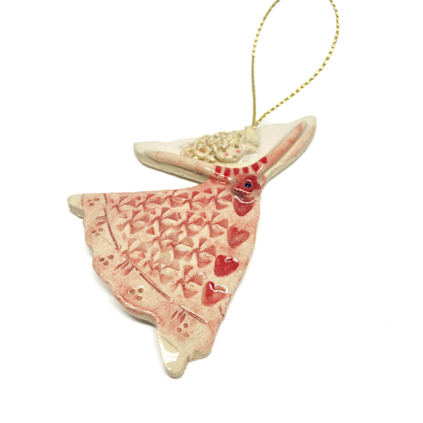 A pink angel ornament with hearts and a gold string, viewed from above.