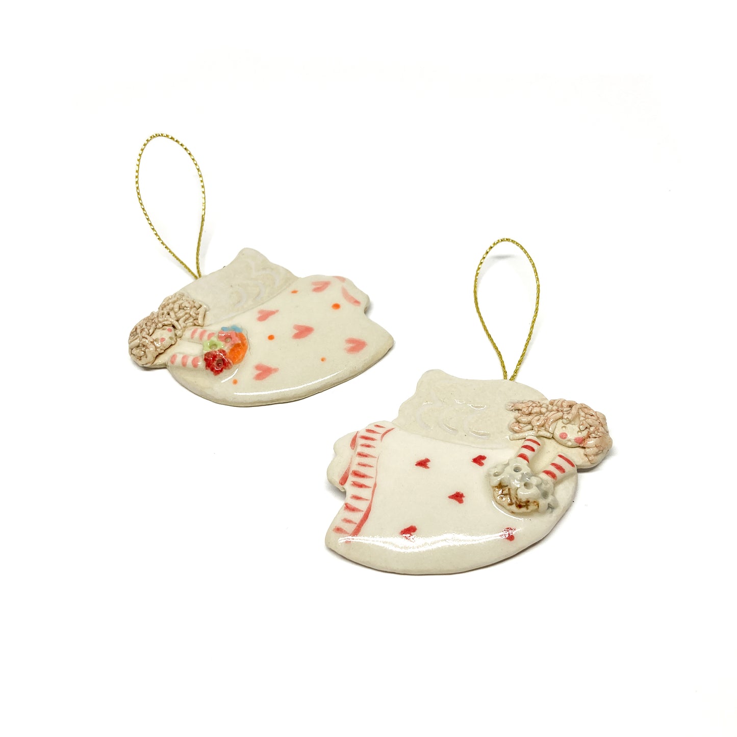 Two white angel ornaments with pink hearts, striped sleeves, and gold strings.