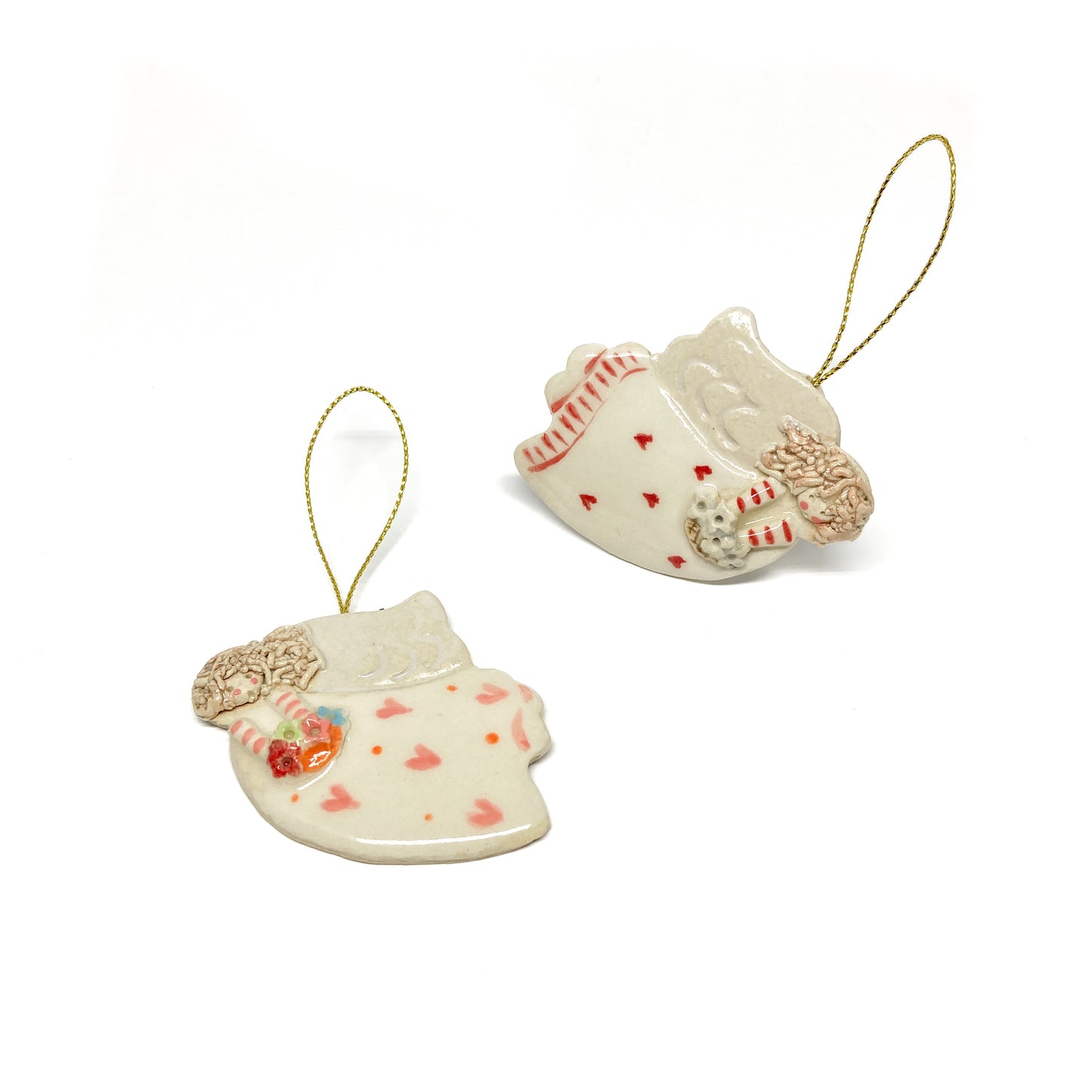 Two white angel ornaments with pink hearts, striped sleeves, and gold strings.