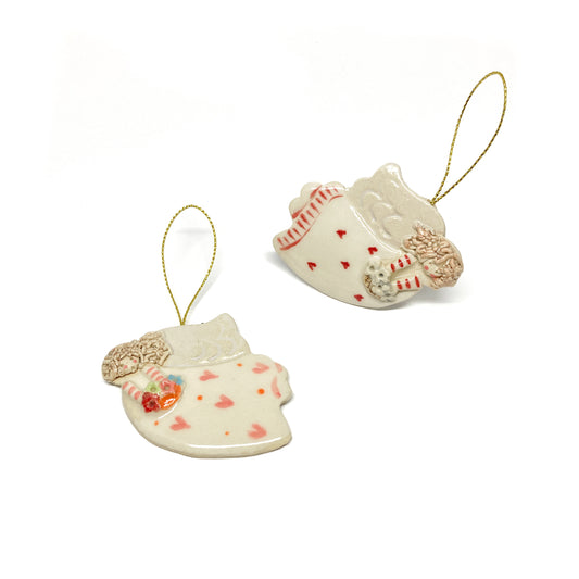 Two white angel ornaments with pink hearts, striped sleeves, and gold strings.