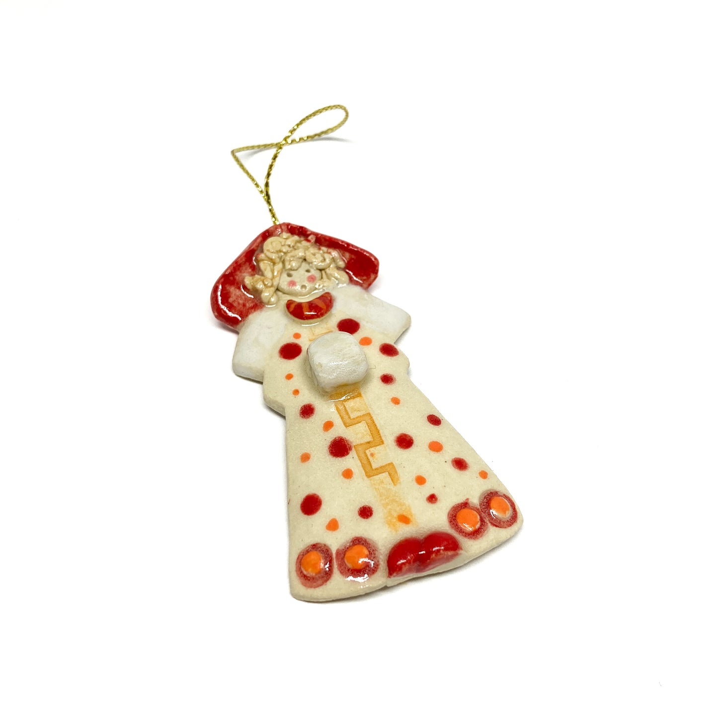 A white angel ornament with red dots, a red hood, and a gold string.