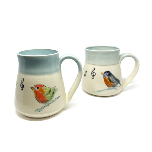 Two ceramic mugs with bird and musical note designs.