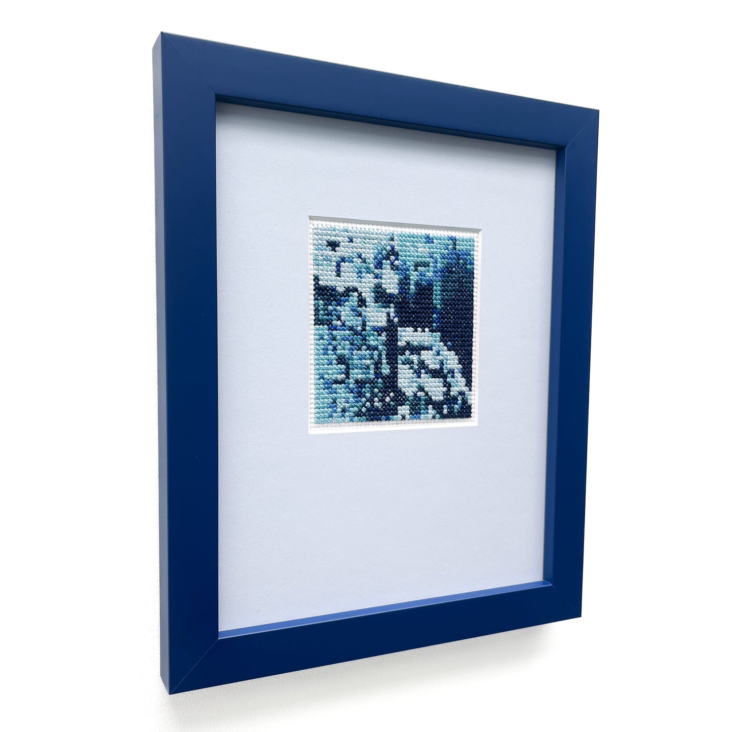 Framed "Blue Monochrome" cross-stitch art, showcasing a textured design in various blue tones.