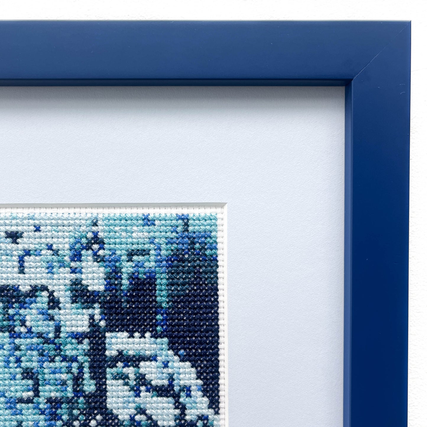 Close-up of the "Blue Monochrome" framed cross-stitch, highlighting the blue threadwork and frame.