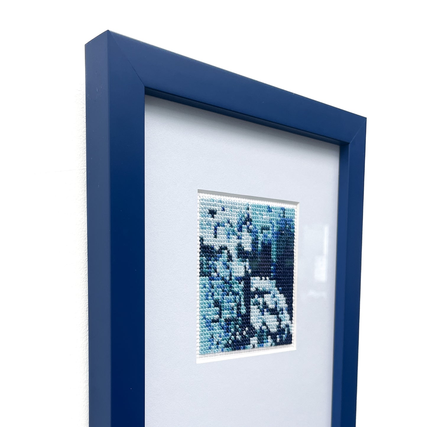 Side view of the framed "Blue Monochrome" cross-stitch art, displaying its depth and blue hues.