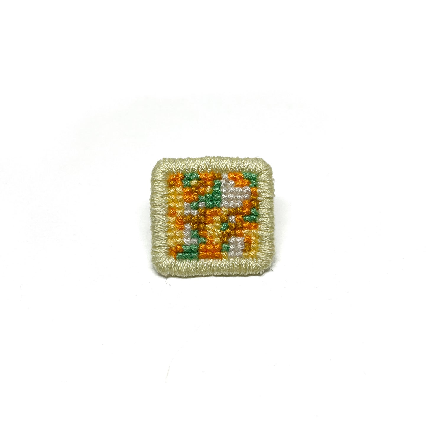 Cross-Stitch Glitch Pin framed in light yellow with bold, mixed embroidery patterns.