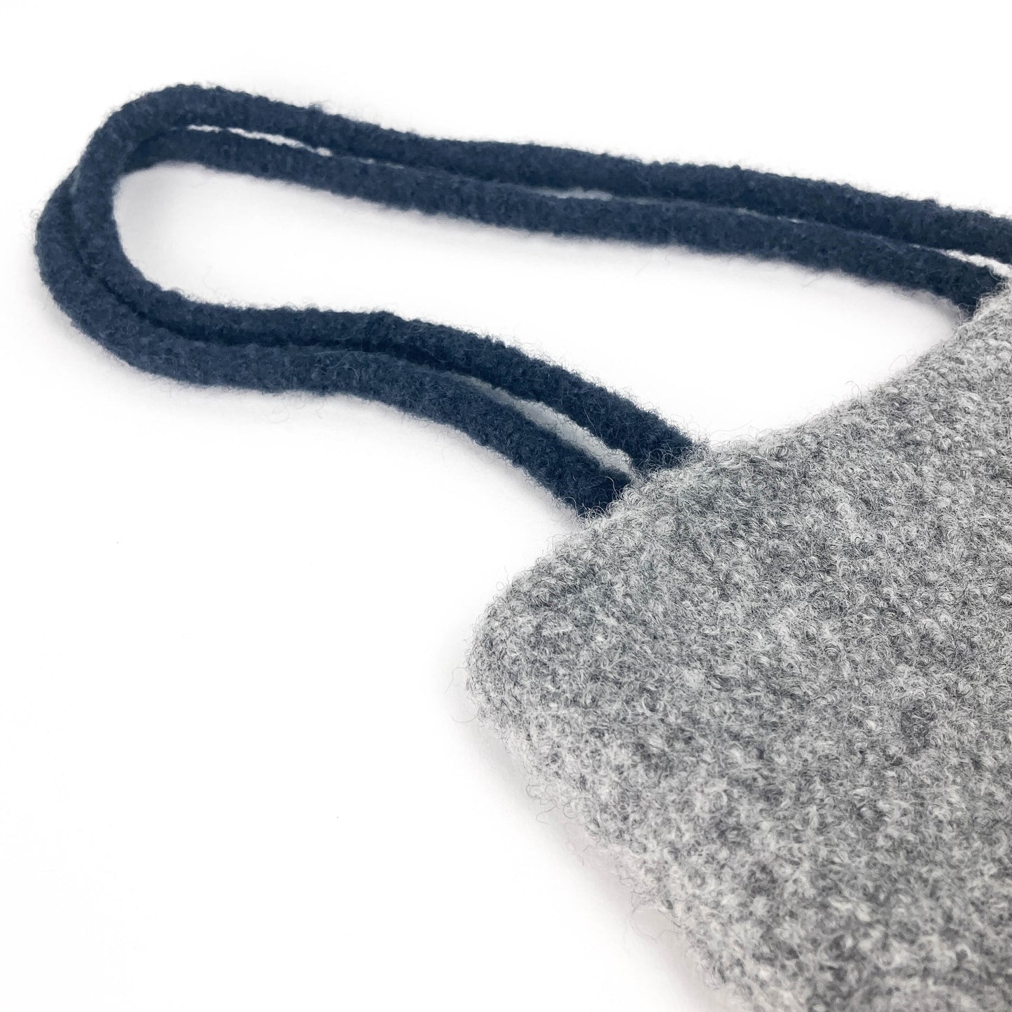 Close-up of a gray felted bag with thick, dark looped handles. The texture of the felt is visible.