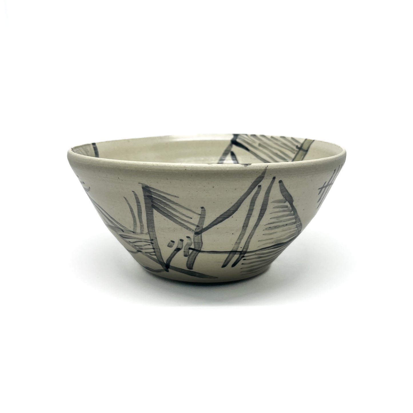 Handmade tea bowl with abstract, dark brushstroke designs on a textured surface.