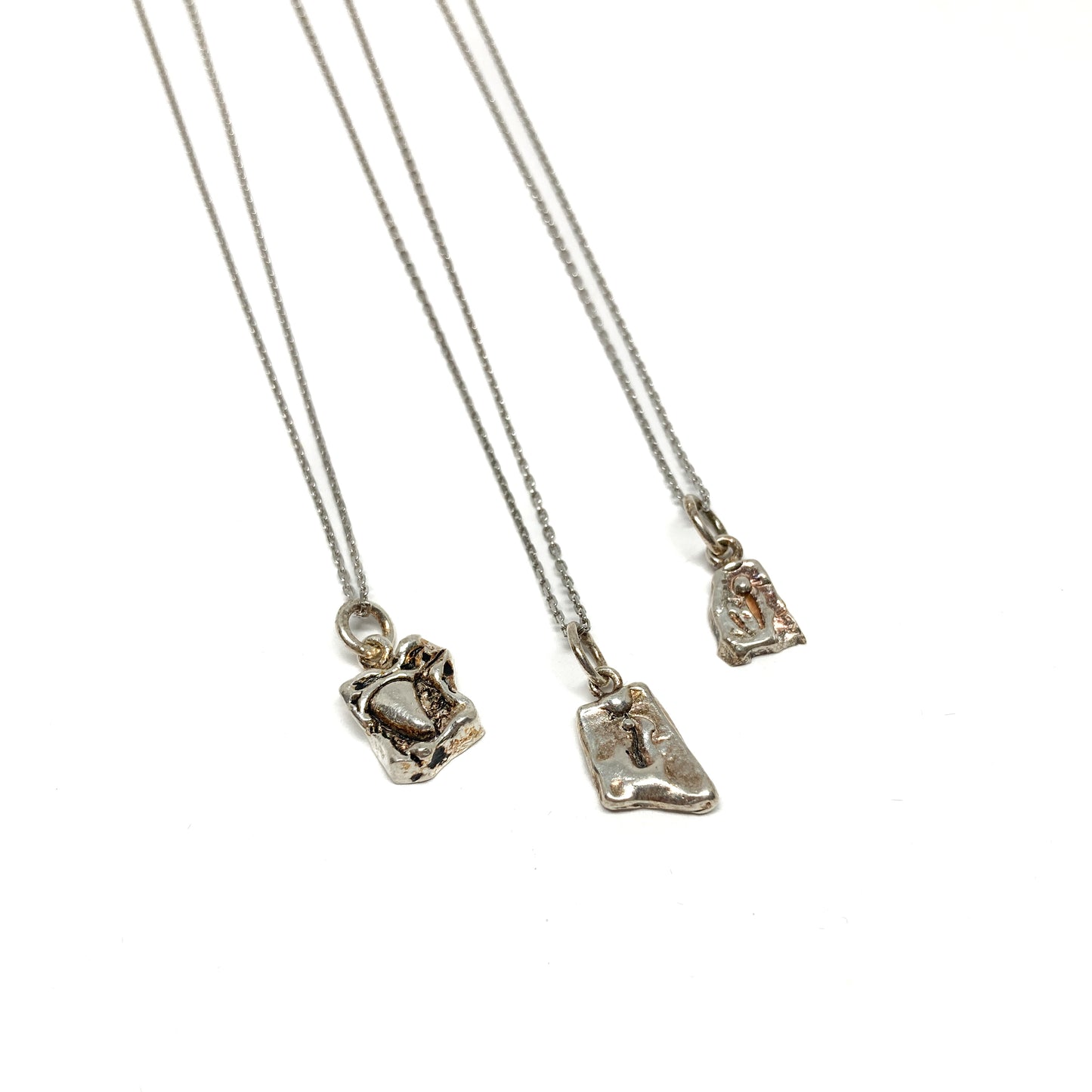 Close-up of three small silver pendants showcasing their textured and engraved details.