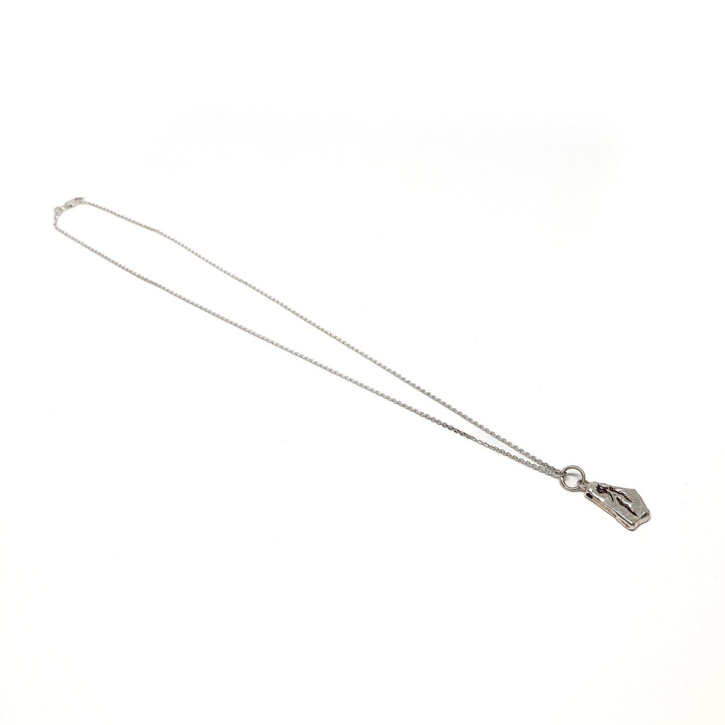 Full view of a delicate silver chain necklace featuring a small abstract pendant.
