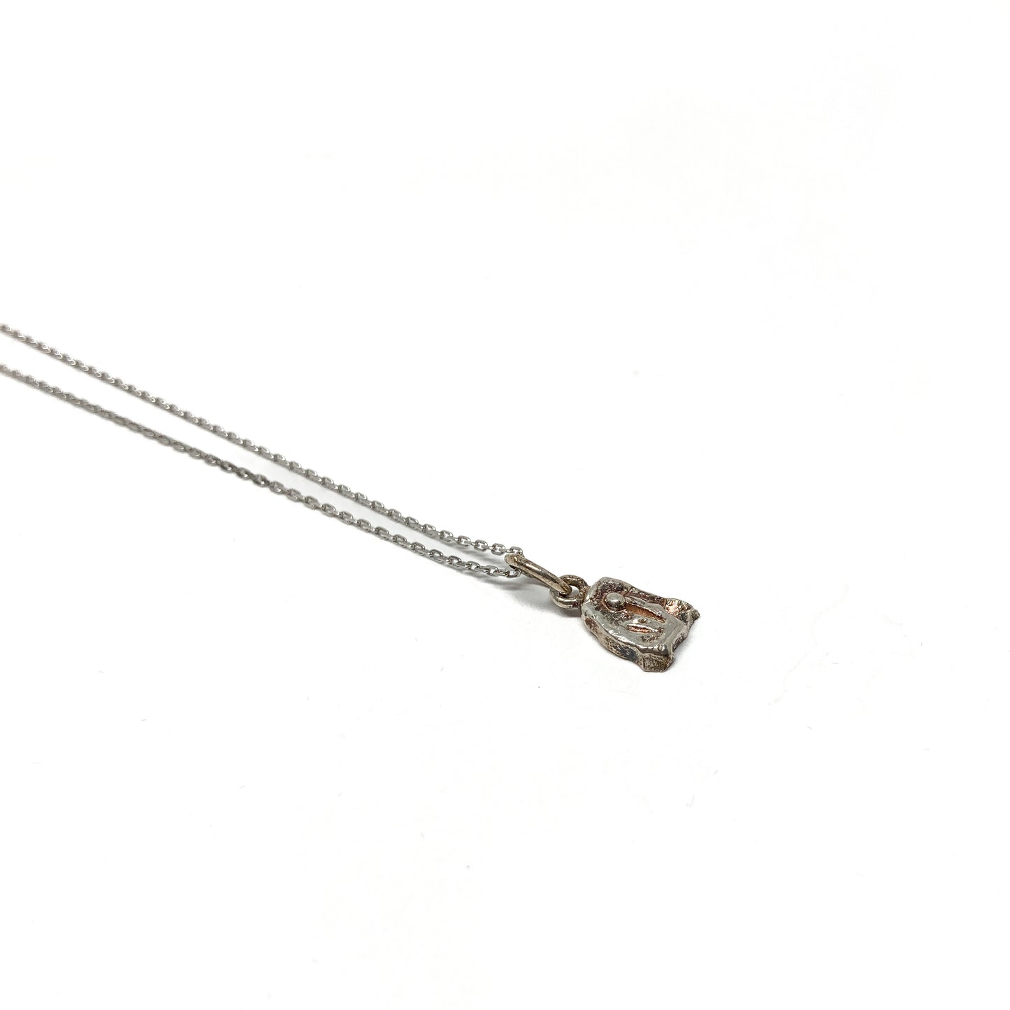 Close-up of a small, textured silver pendant.