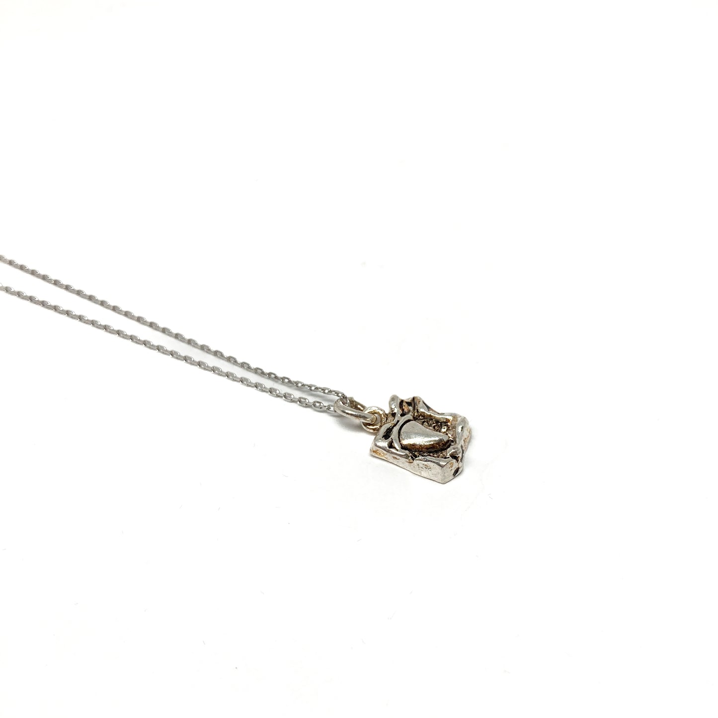 Close-up highlighting the details of a small silver pendant.