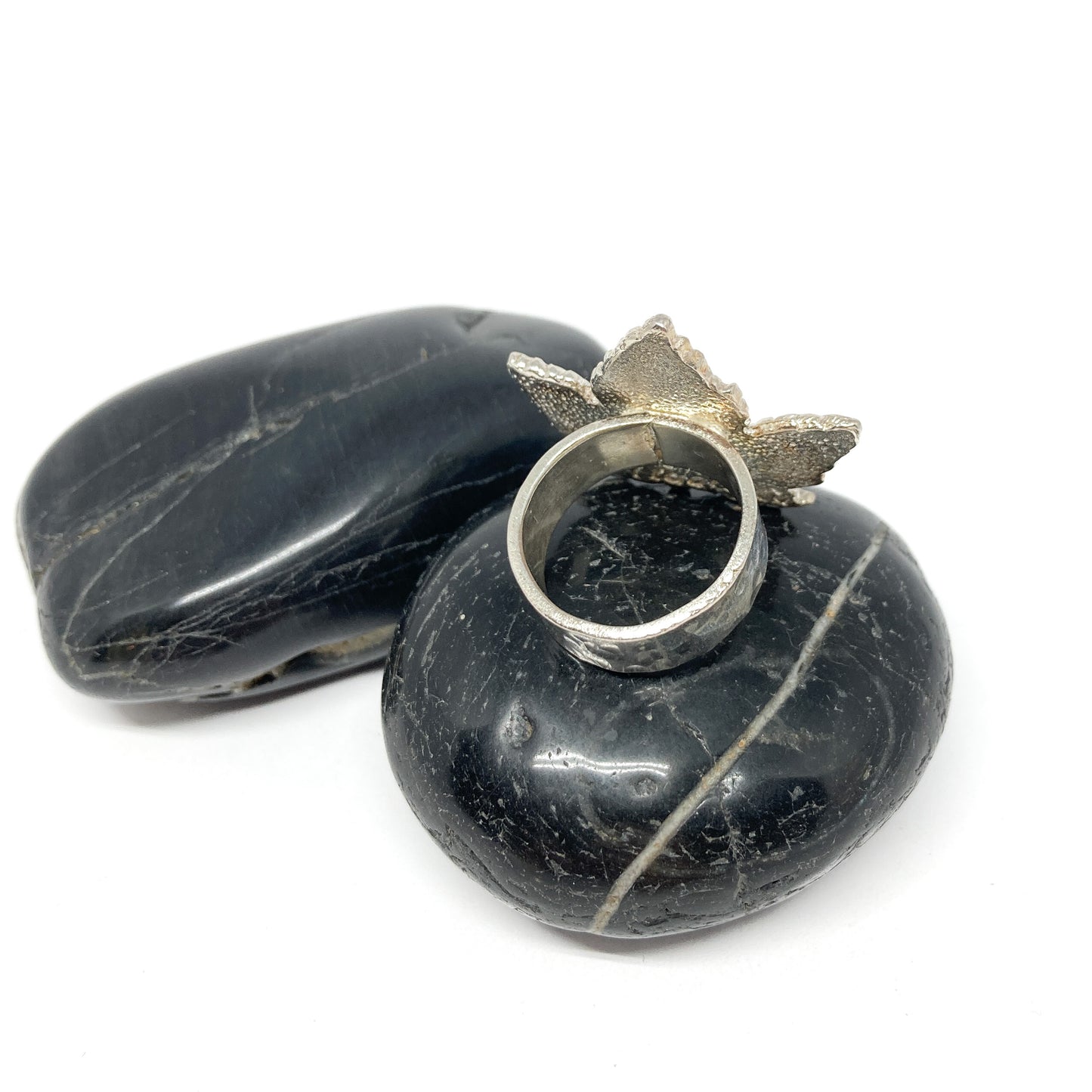 Back view of a silver maple leaf ring on a striped, dark stone.