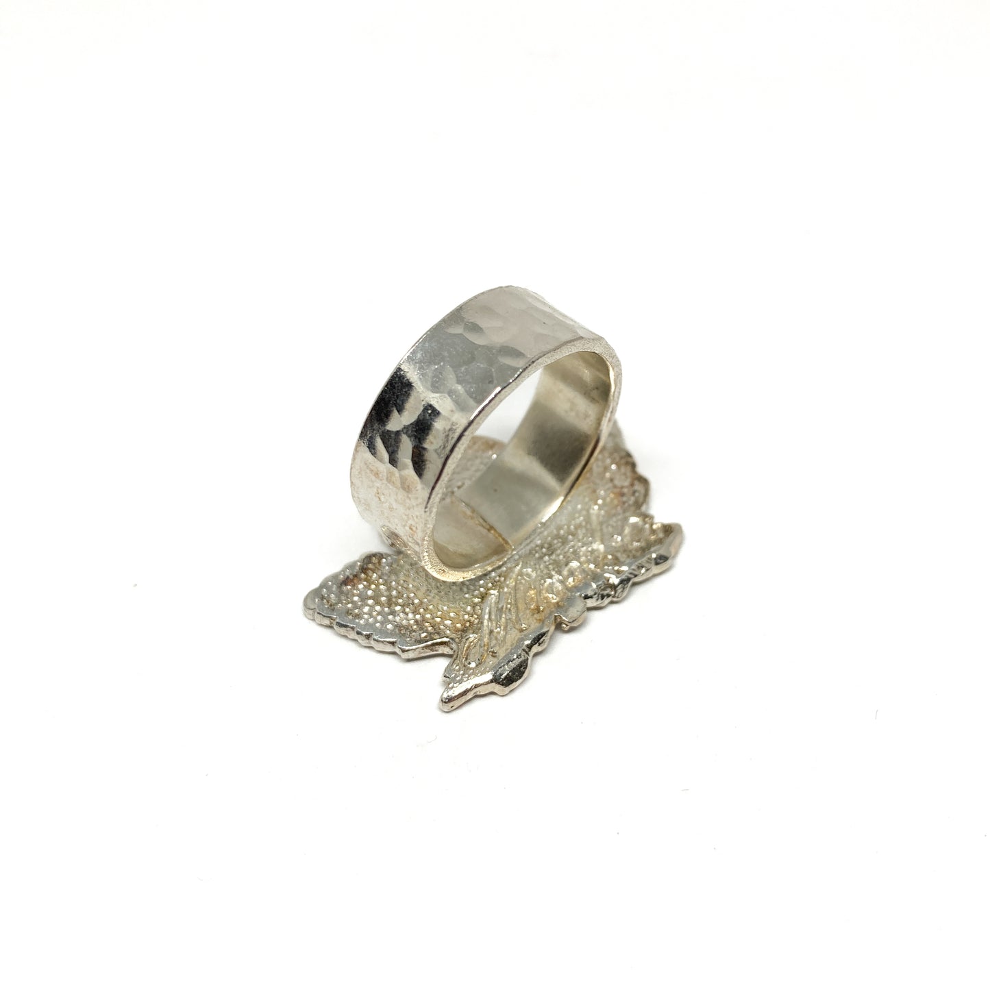 Underside of a silver maple leaf ring with a wide, textured band.