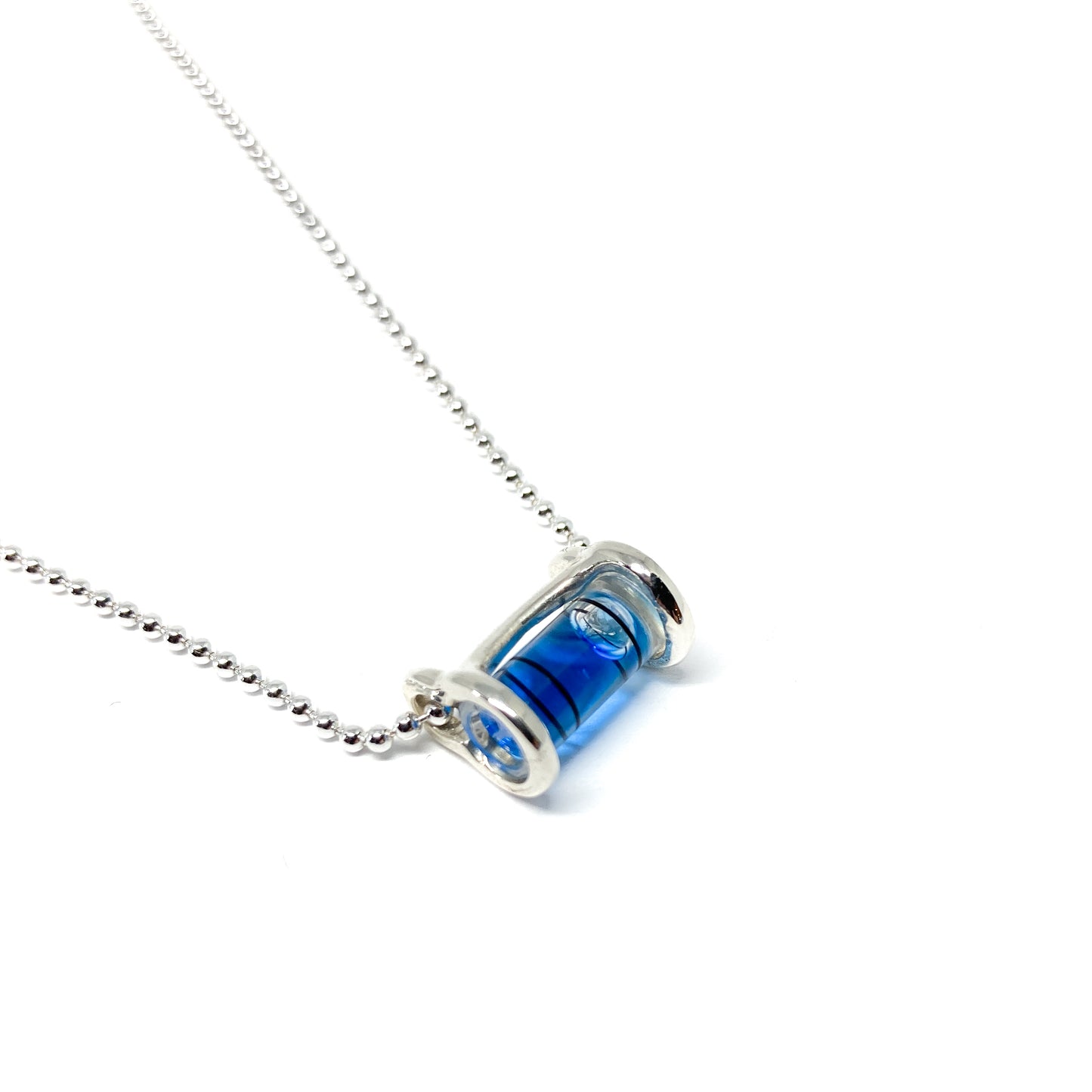 Silver necklace with a horizontal cylindrical glass pendant filled with swirling bright blue pigment and a visible air bubble.