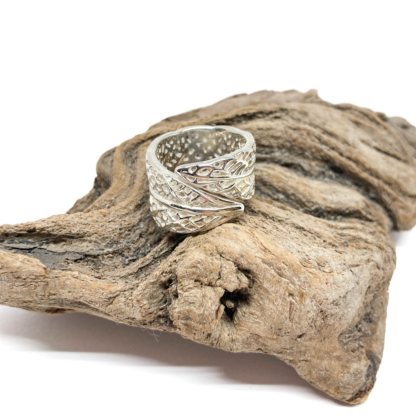 Silver Lace Leaf Ring resting on a textured piece of driftwood. Openwork leaf design.