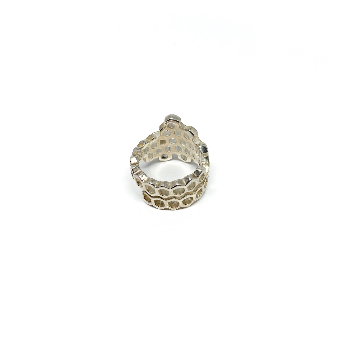 A shiny silver ring shaped like a honeycomb is viewed from the back, showing its intricate hexagonal cells.