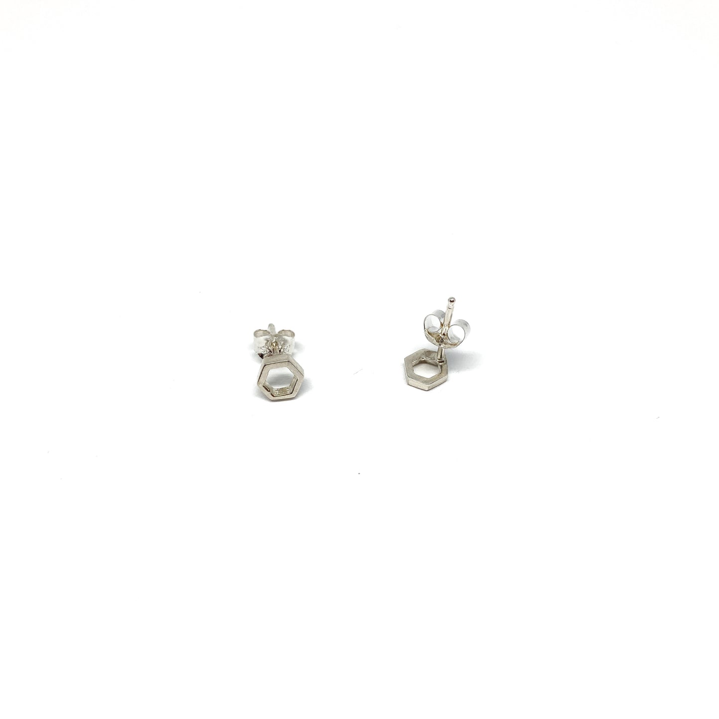Two shiny silver stud earrings, each a small open hexagon with a post and butterfly back, are shown.