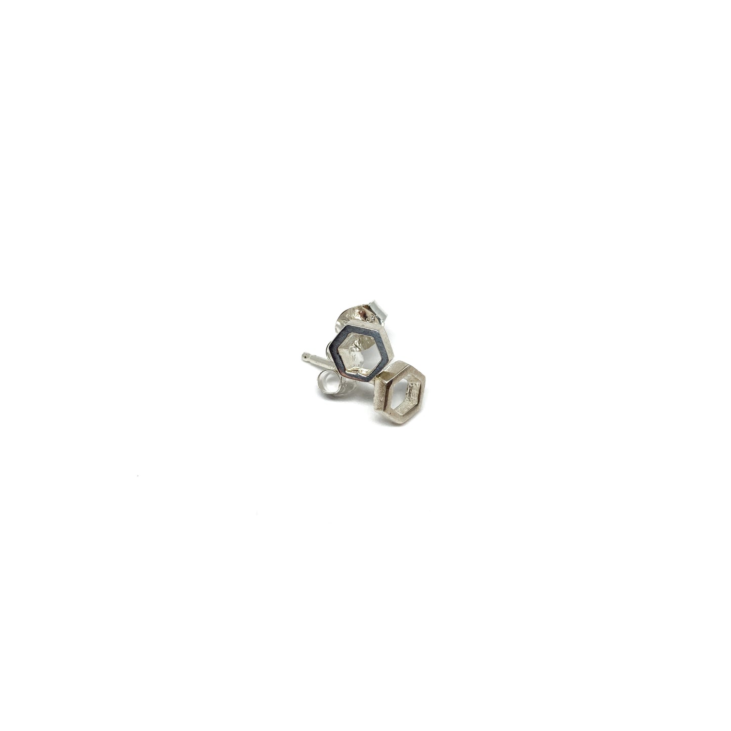 A pair of shiny silver stud earrings, each featuring a small, open hexagonal design, are shown close-up.