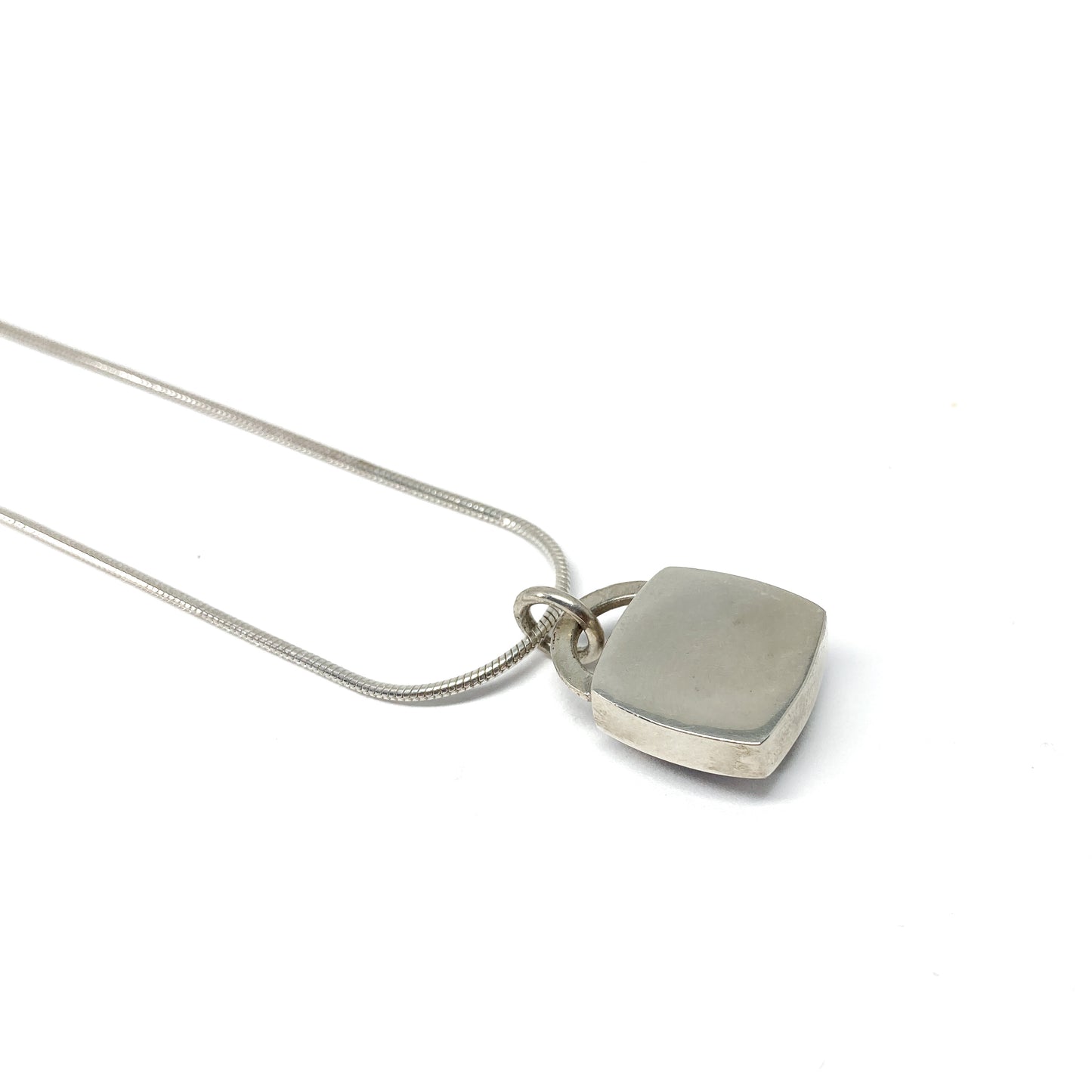 A silver snake chain necklace features a square pendant with a smooth, slightly domed surface.