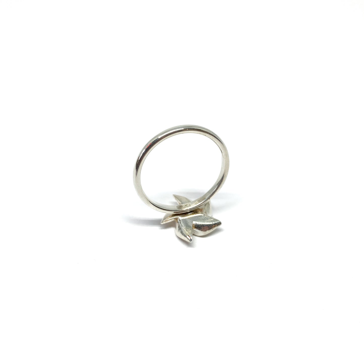 A shiny silver ring features a three-dimensional, stylized floral or pinwheel design attached to the band.