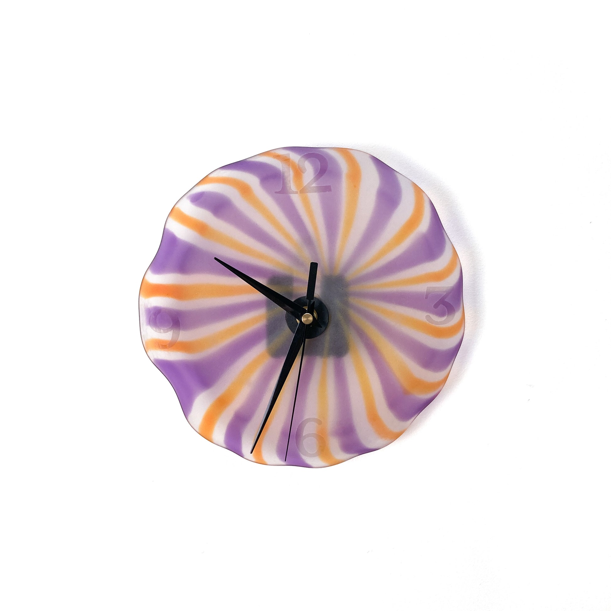 A round glass wall clock with radiating stripes of orange, purple, and white, featuring black hands and silver numerals.