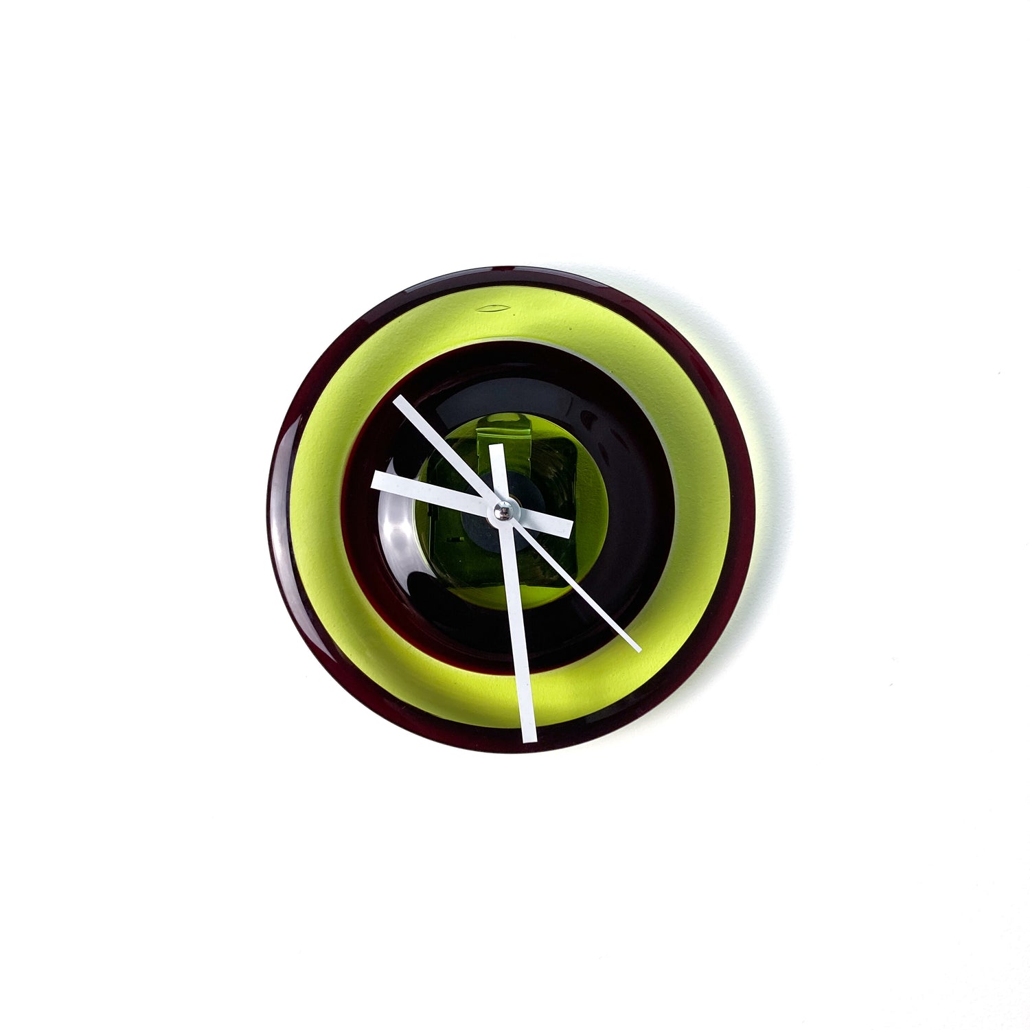 A round glass wall clock with concentric rings of lime green, dark red, and black, featuring white hands and no numerals.