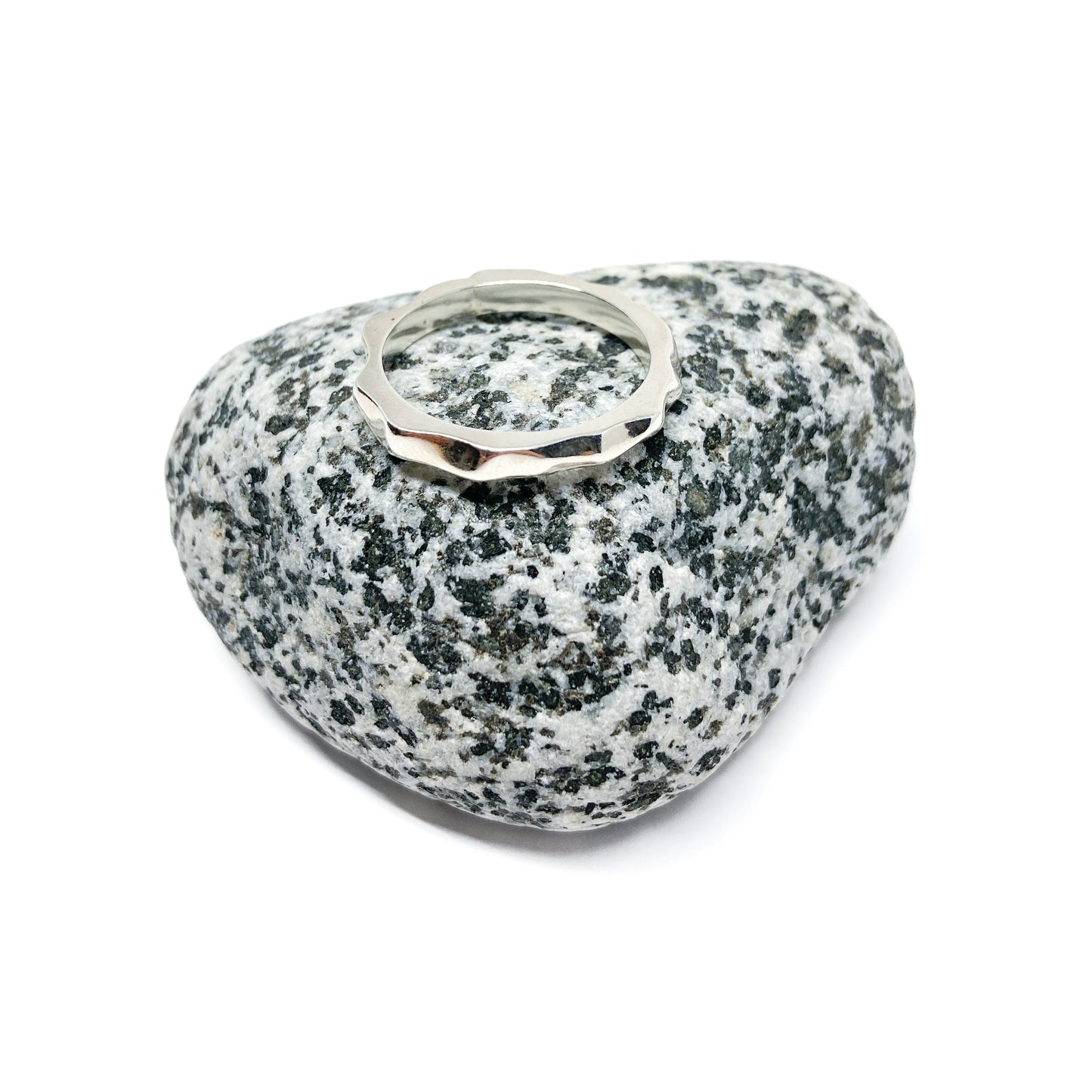 Silver ring on textured gray stone, close-up view.