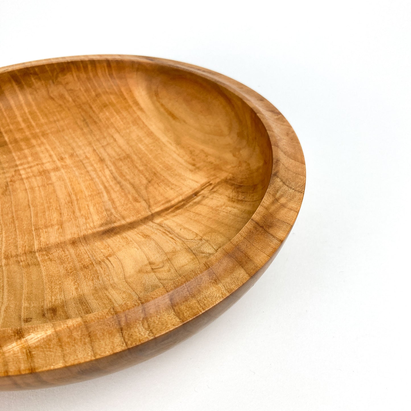 Angled close-up of a maple bowl highlighting its curved interior and rim.