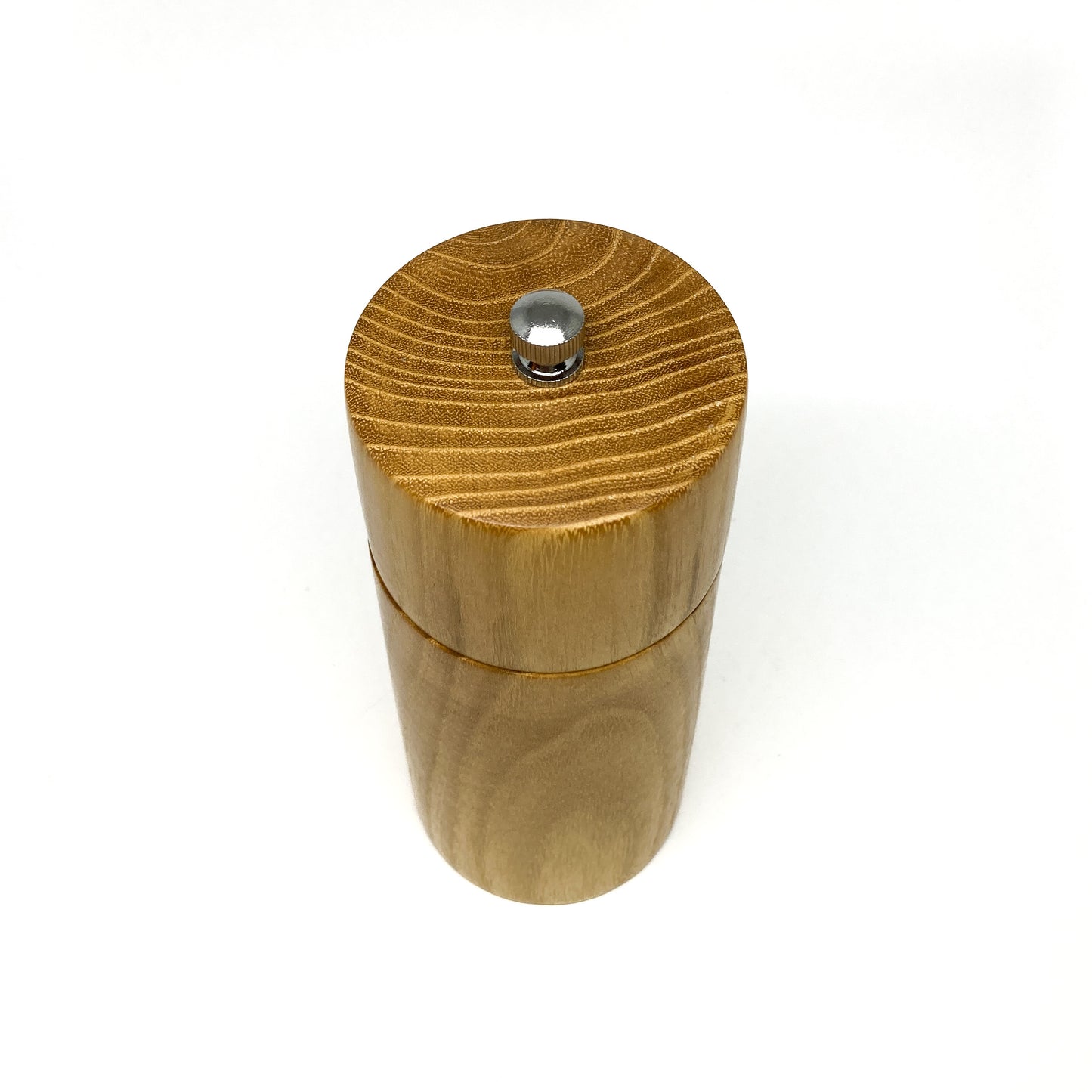 A Danish Black Locust Pepper Grinder is viewed directly from the top, emphasizing the wood grain and metallic adjustment knob.