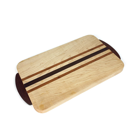 Angled view of a Striped Eastern Maple Cutting Board with light wood and two darker wood stripes, showing rounded corners.