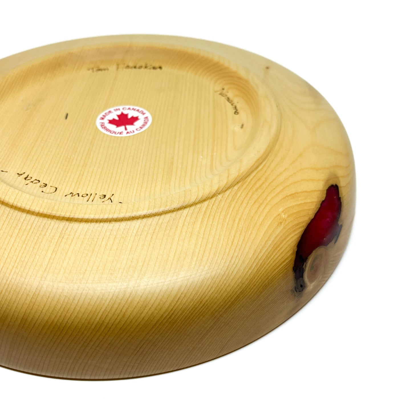 Underside of a yellow cedar candle tray, showing a "Made in Canada" sticker and red epoxy highlight.