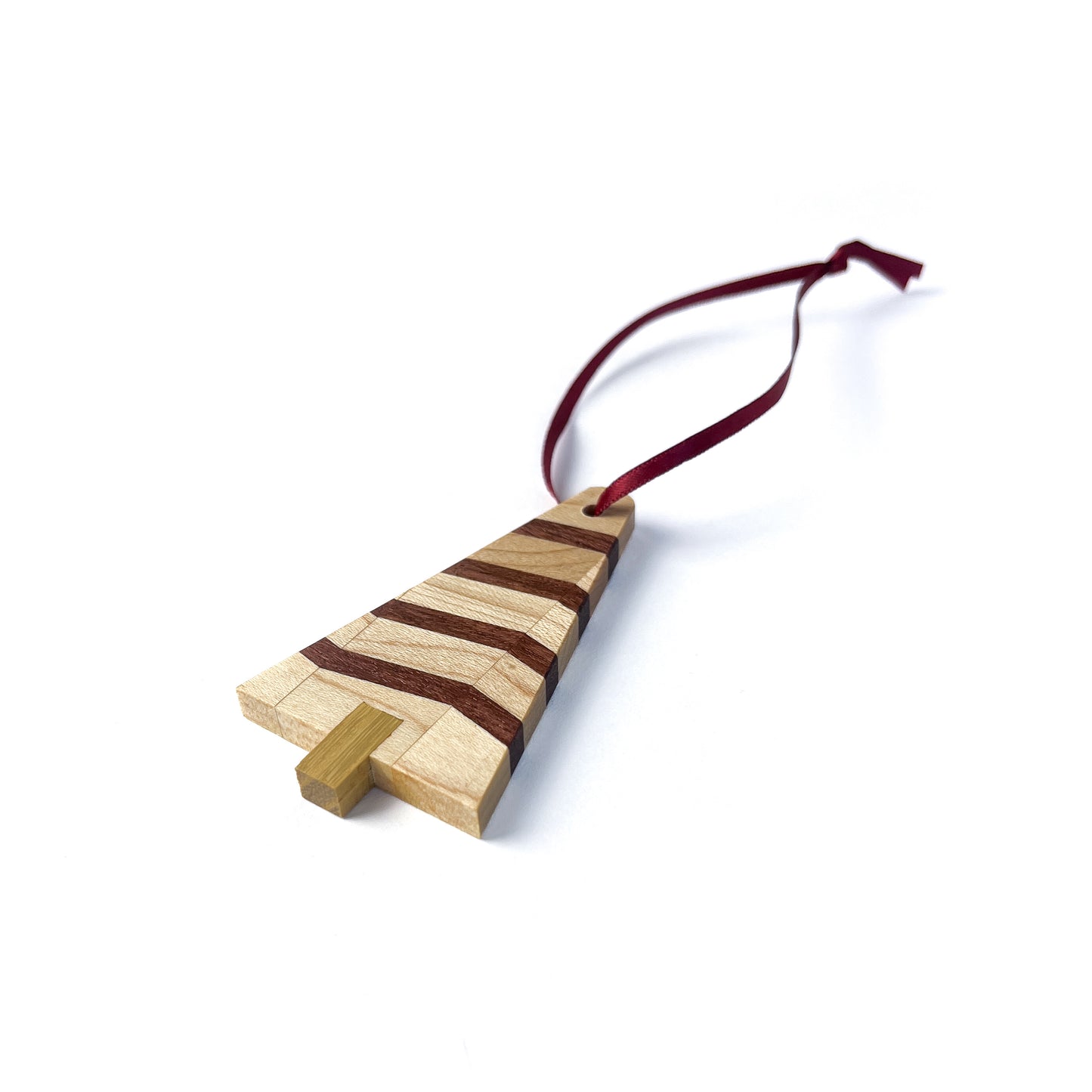 A wooden Christmas tree ornament with light and dark striped wood, featuring a light-colored trunk and a red ribbon.