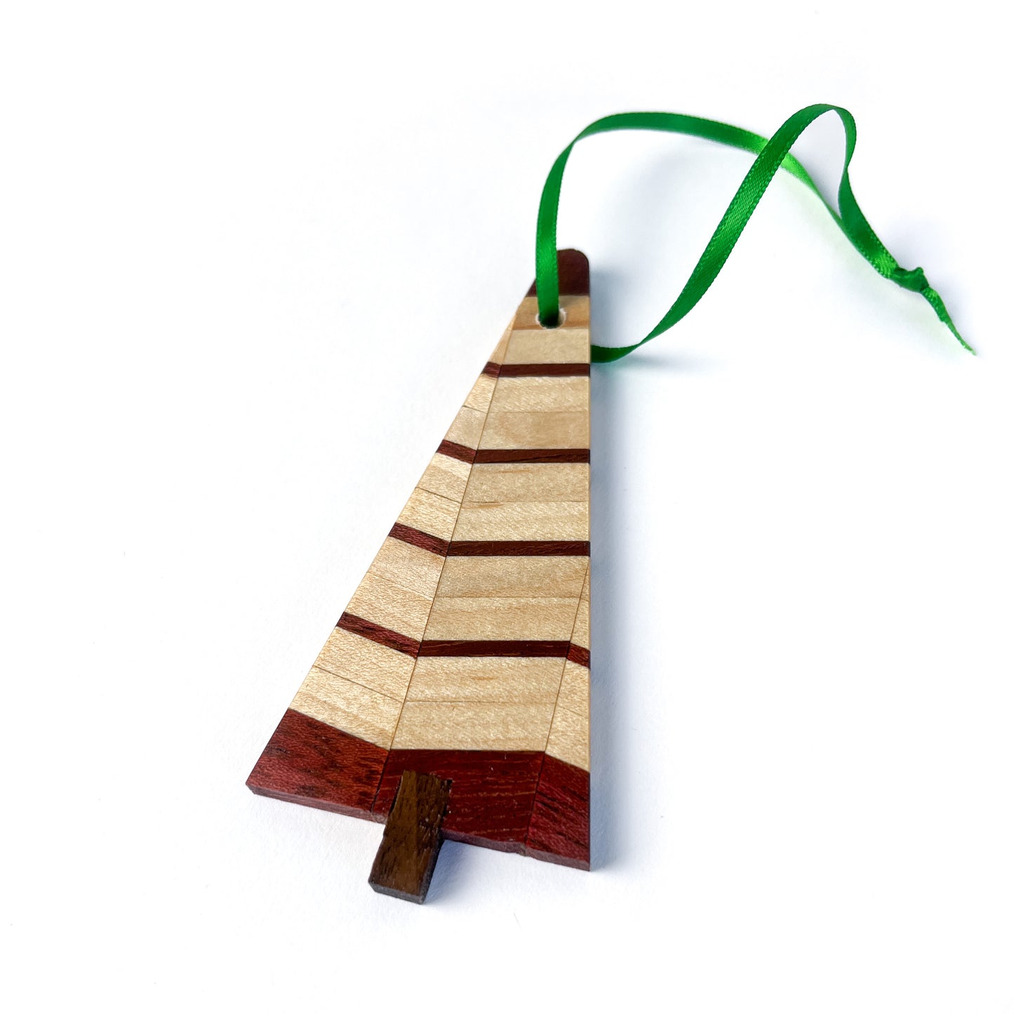 A single wooden Christmas tree ornament featuring light and dark wood stripes, suspended by a green ribbon.