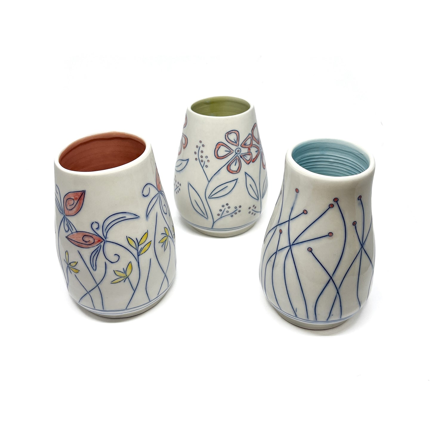 Three handmade pottery vases with unique hand-painted floral designs and contrasting interior colors (red, green, and blue).