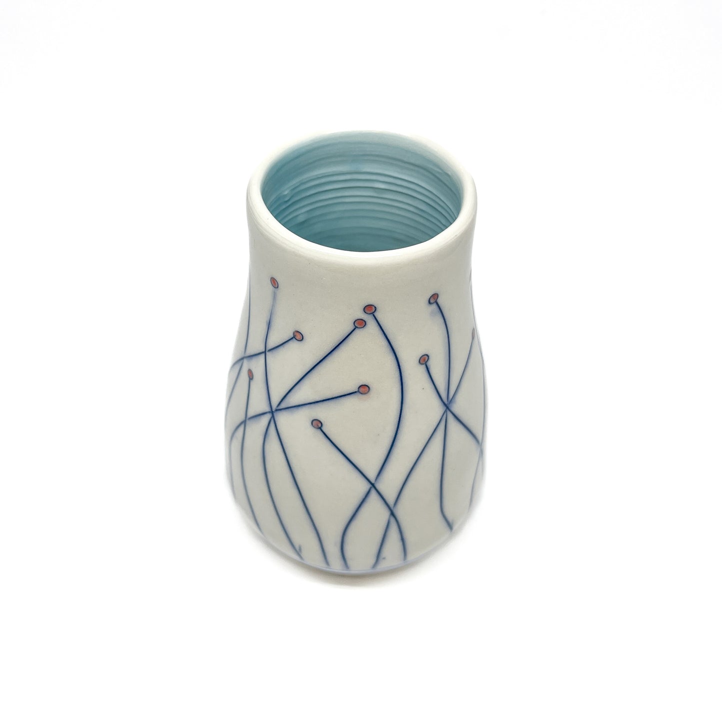 A white ceramic vase with a light blue inner glaze features blue line drawings of stems with small red circular details.