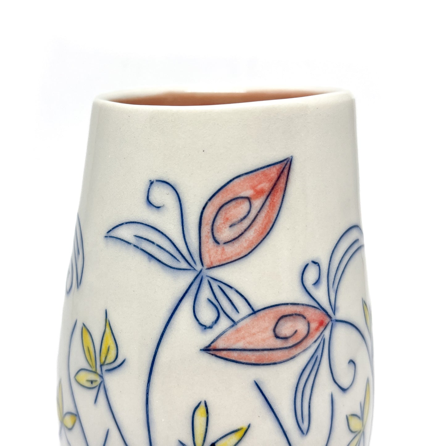 Close-up of a white ceramic vase showing blue outlined floral designs with reddish-orange and yellow petal details. The inner glaze is light brown.