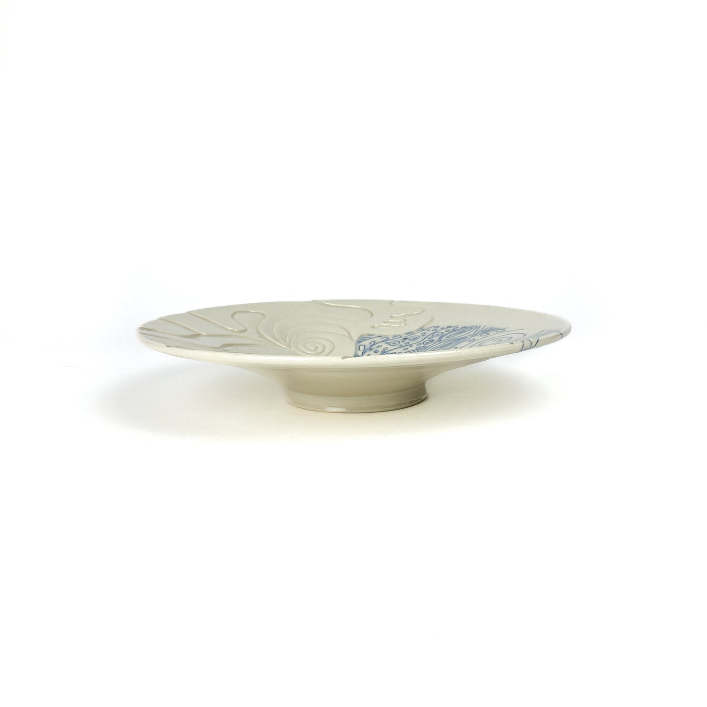 Low ceramic plate with abstract blue and textured white designs.