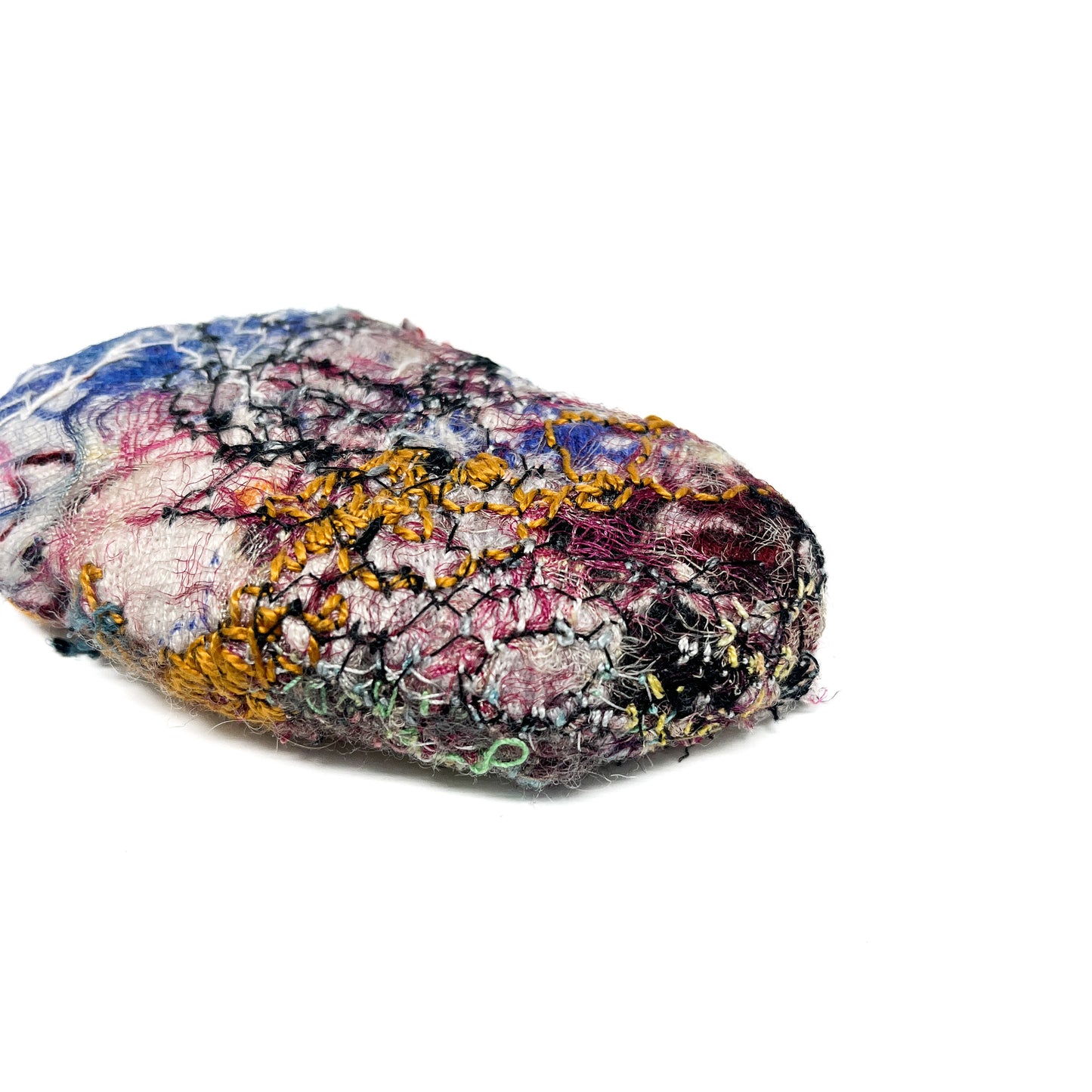 Embroidered Rock by Jane Kenyon: Textured textile art resembling a rock, with intricate stitching in blue, pink, yellow, black, and green threads.