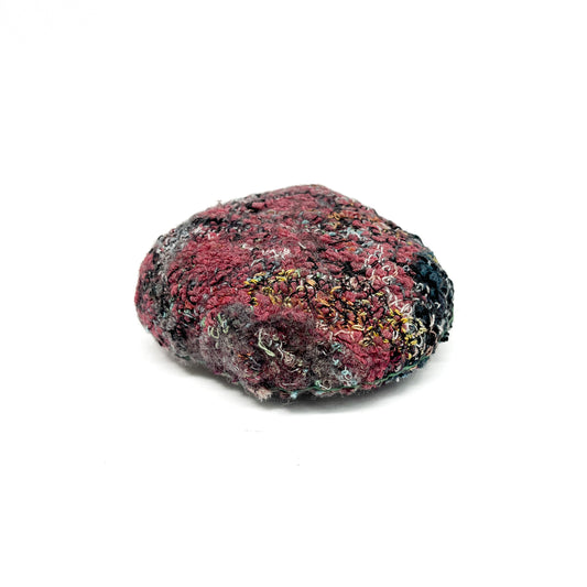 Embroidered Rock: Round textured textile art resembling a rock, with rich red, black, and yellow thread stitching.