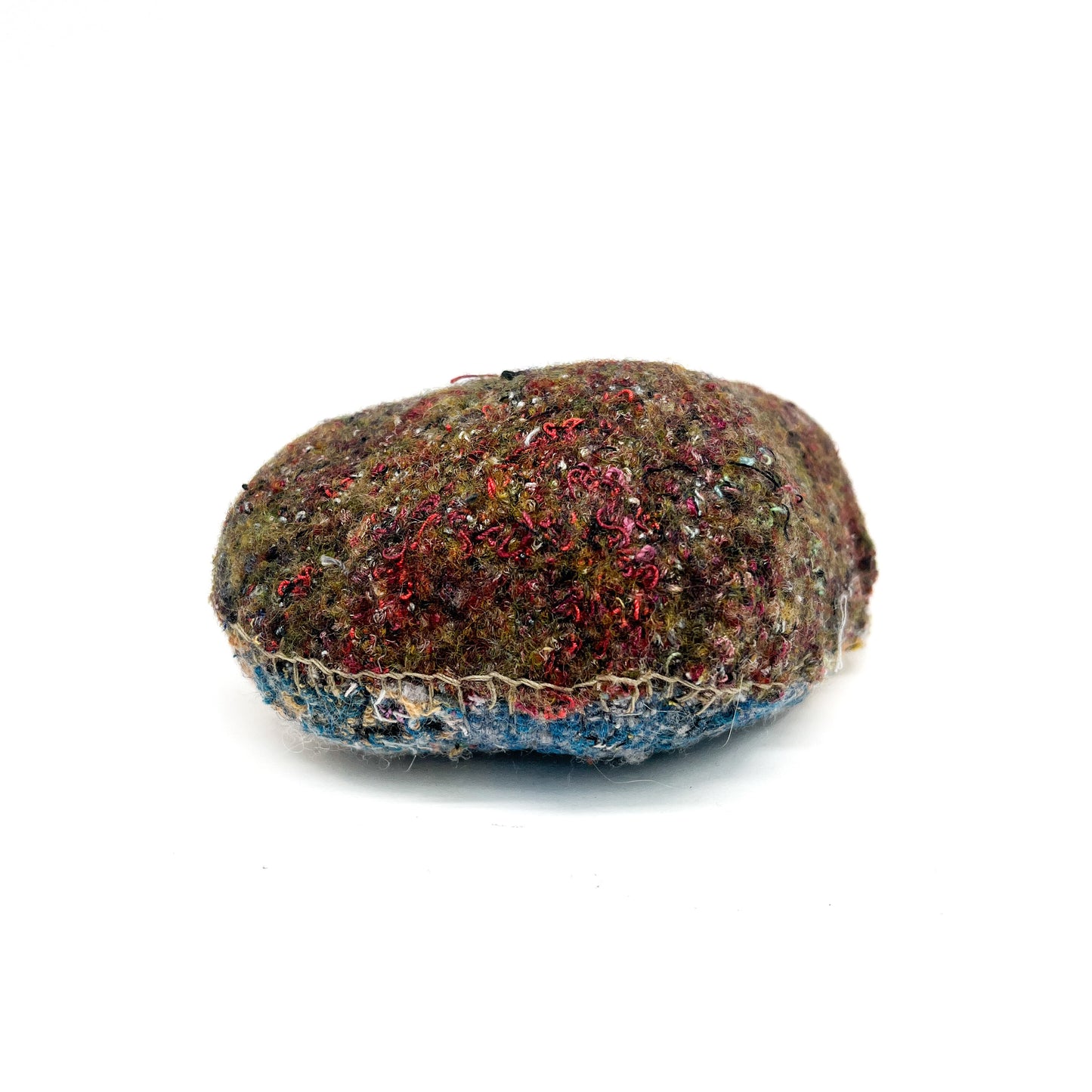A rock with a dense, textured surface created by layers of colorful, interwoven threads and stitching.