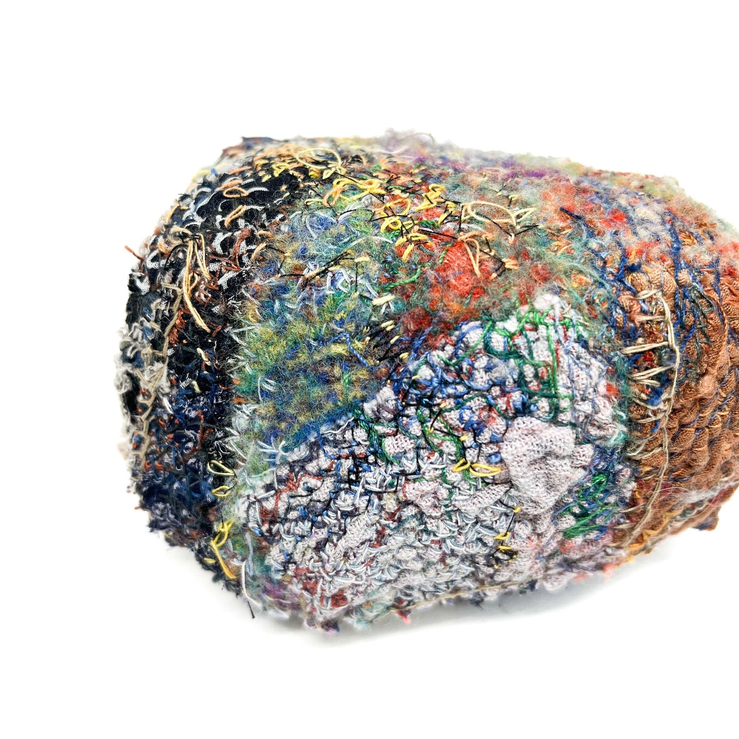 A stone by Jane Kenyon, displays a textured surface of colorful, dense embroidery and stitching.