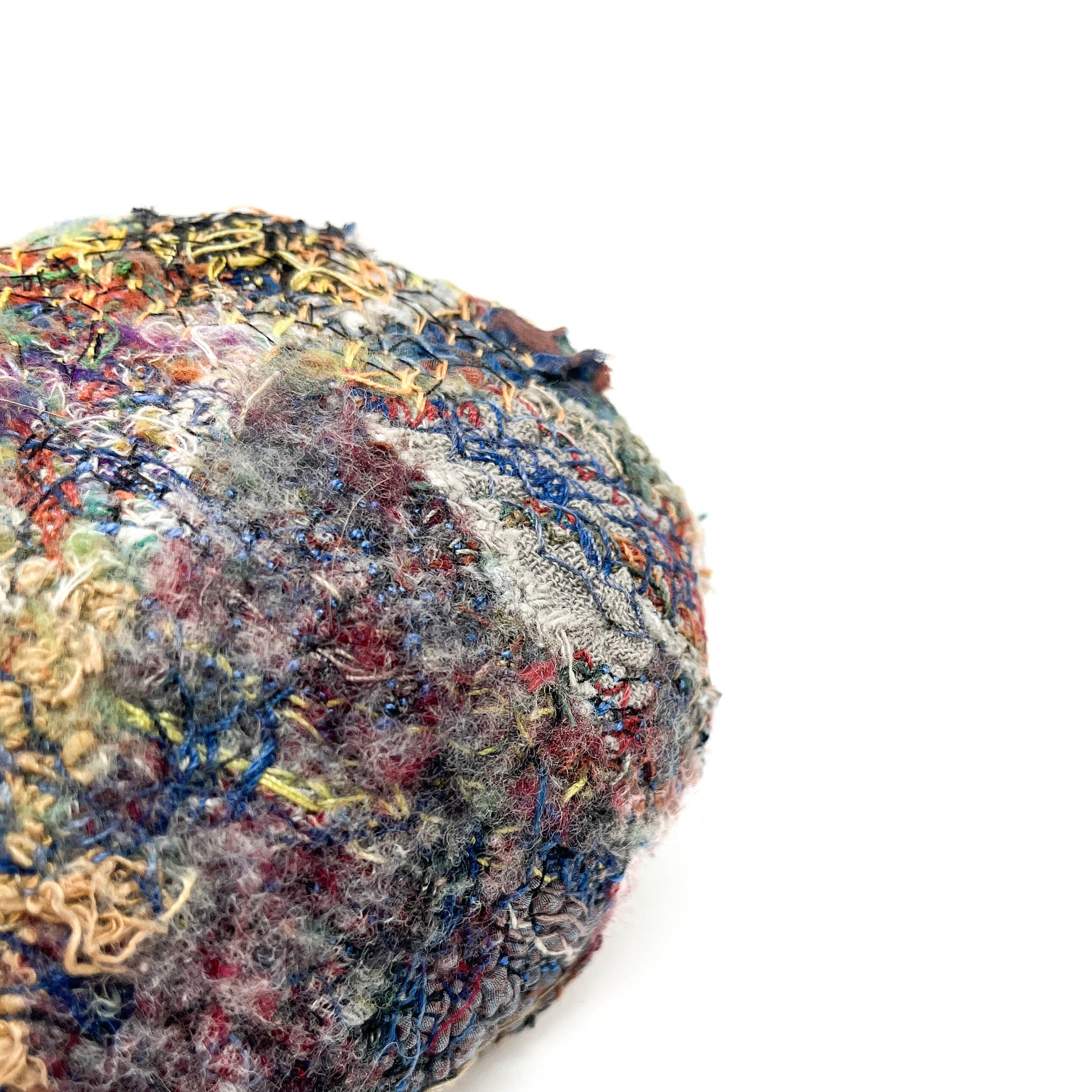 A stone by Jane Kenyon, showcases a textured surface of colorful and intricate embroidery and stitching.