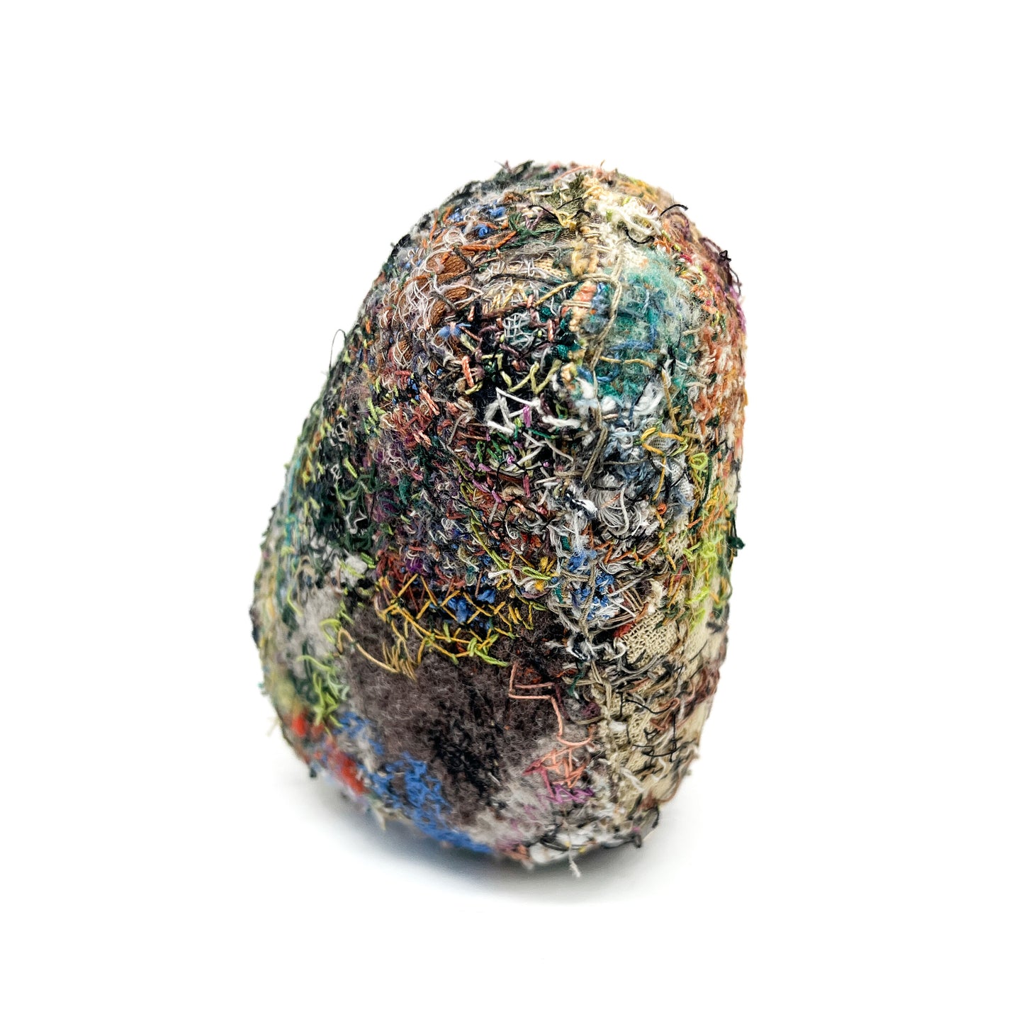 A stone with a richly textured surface created by layers of colorful and dense embroidery and stitching.