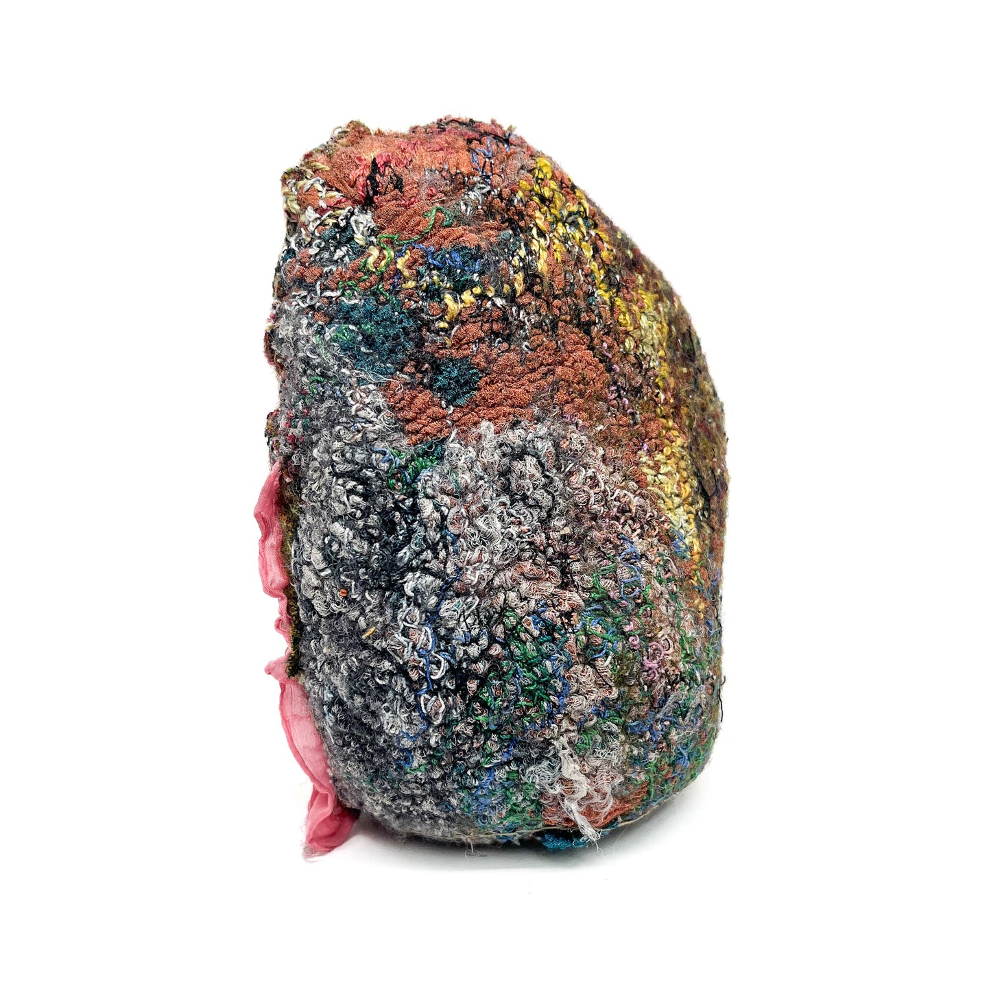 A close-up shows the textured surface of a stone covered in colorful, detailed embroidery and stitching.