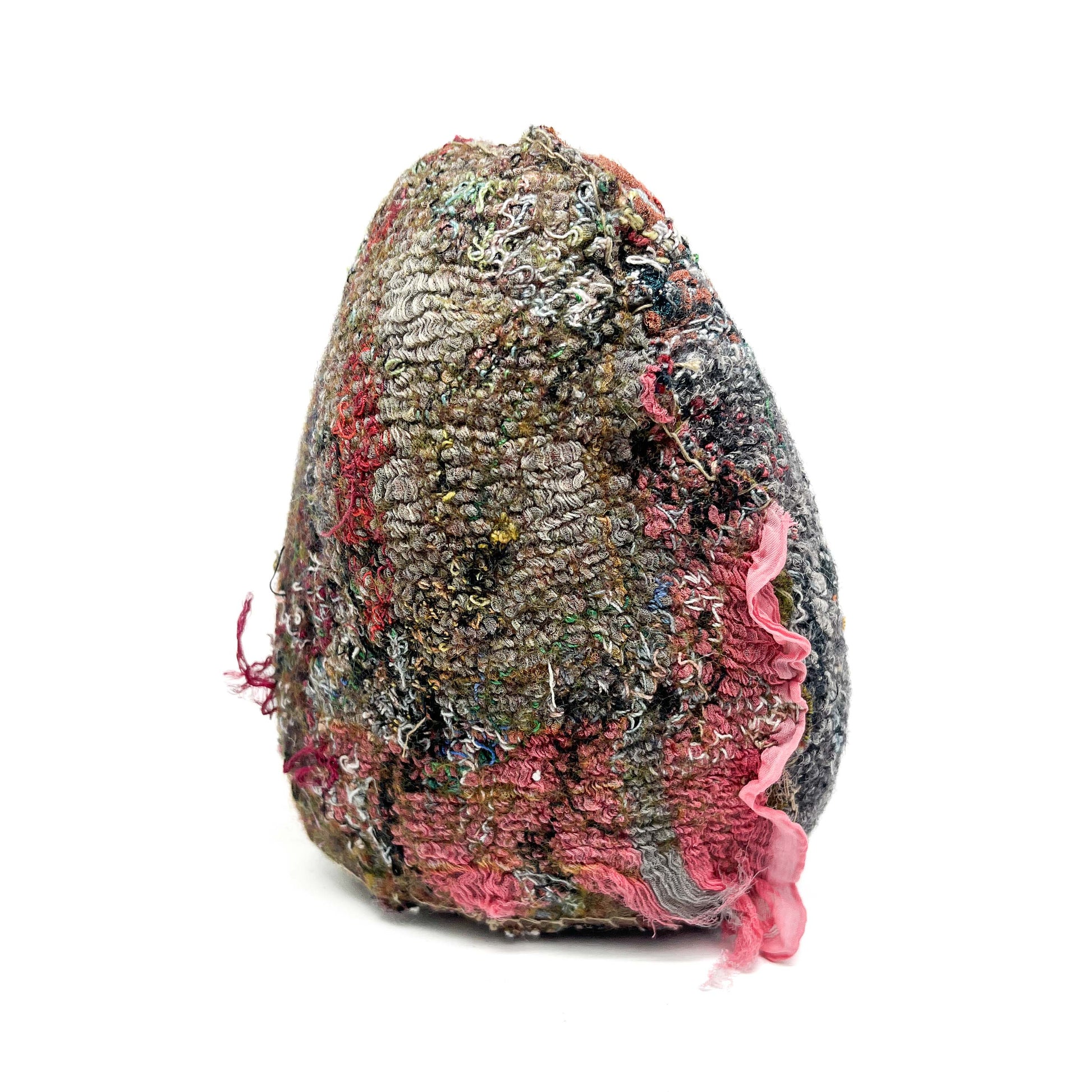 A textured stone features layers of colorful and dense embroidery and stitching, with a soft pink fabric detail.