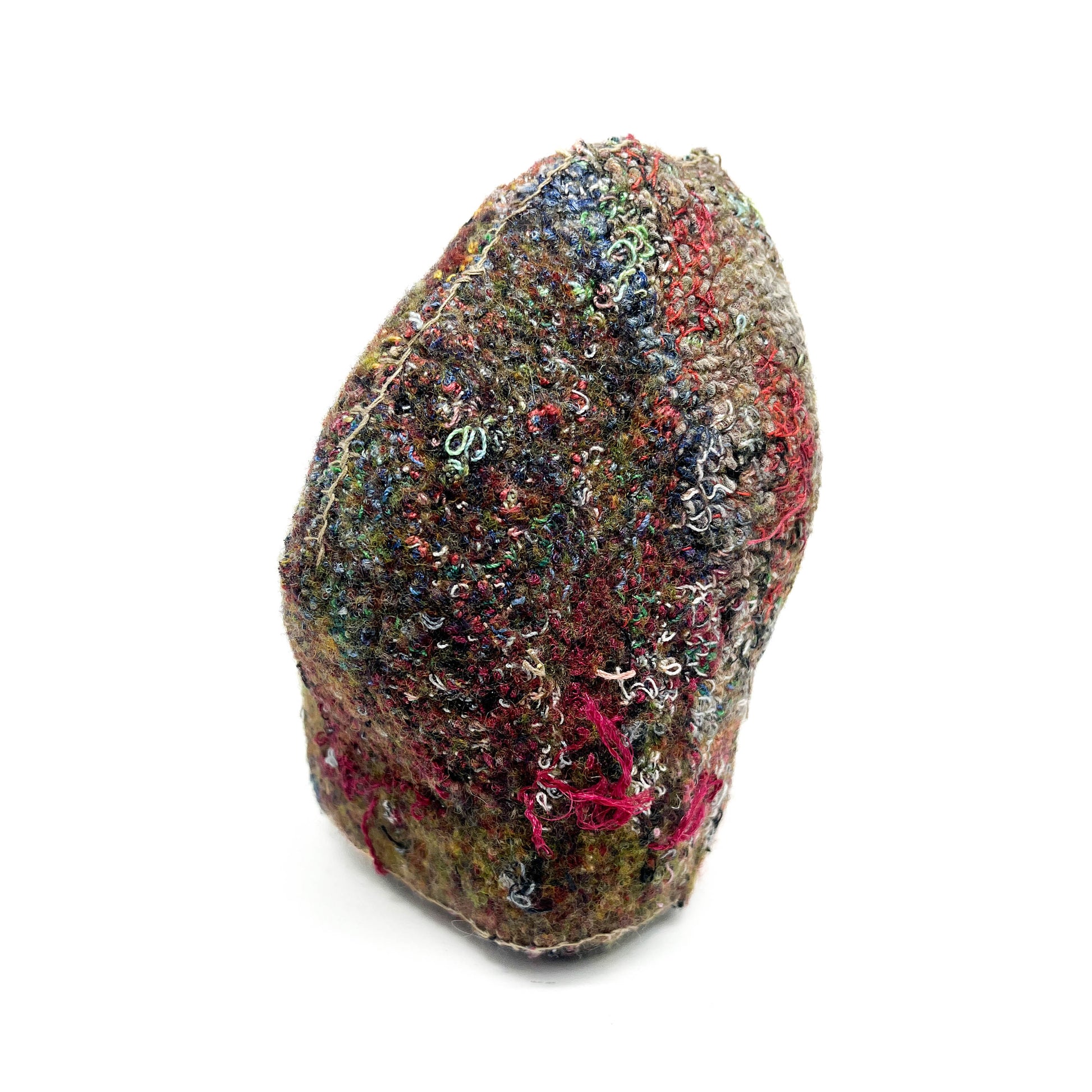 A textured stone features a dense surface of colorful and elaborate embroidery and stitching.