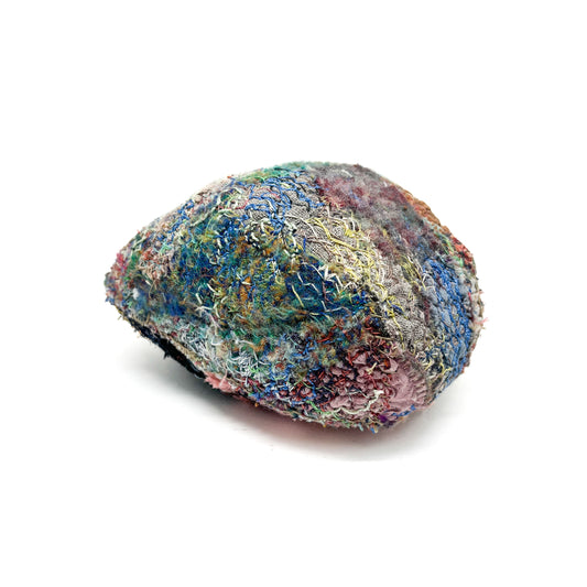 A textured stone displays a vibrant and intricate surface of colorful embroidery and stitching.