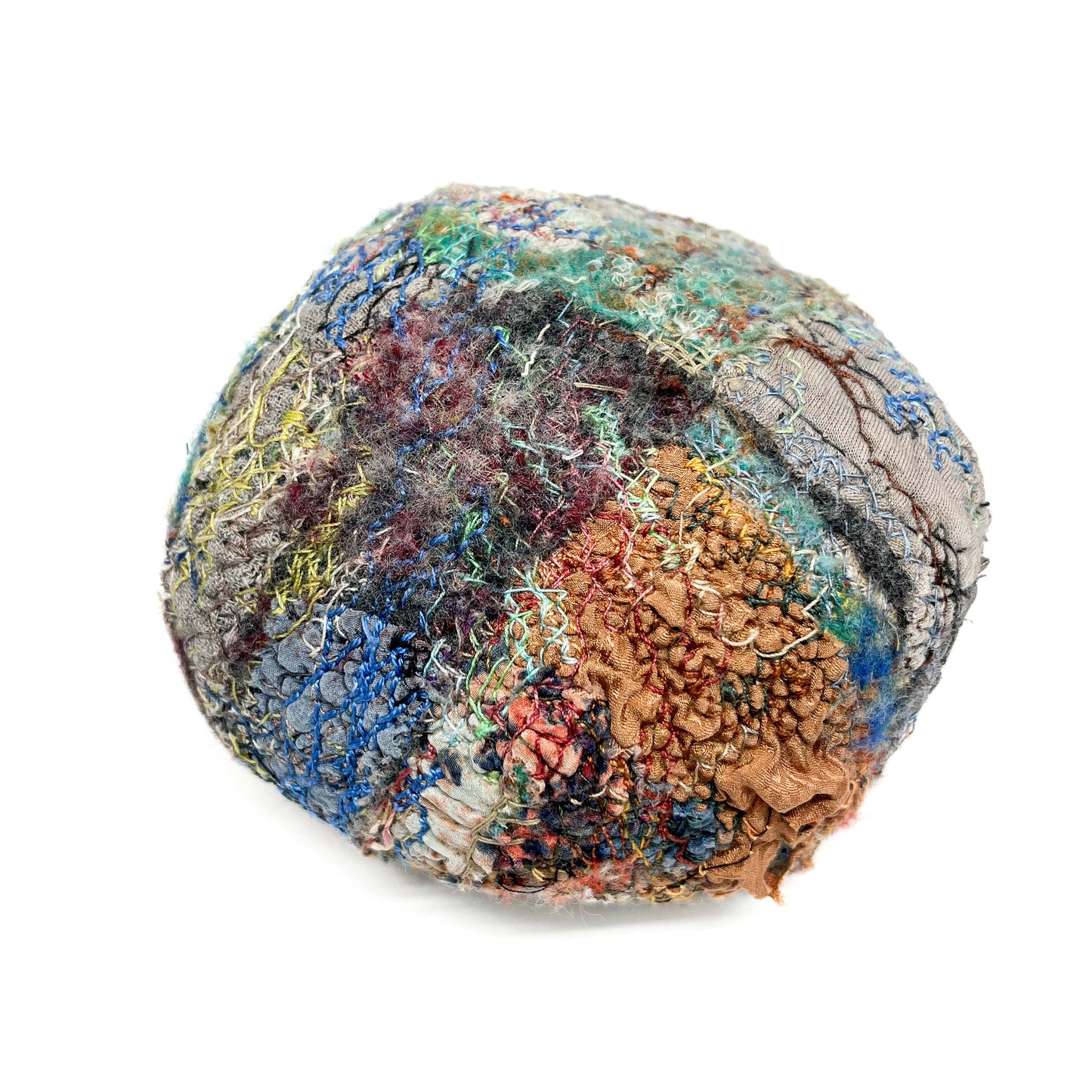 A round, textured stone features a complex and colorful arrangement of embroidery and stitching.
