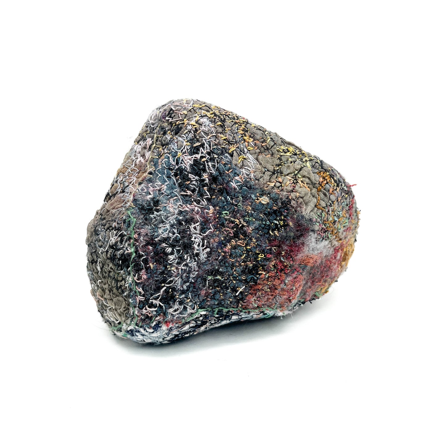 A textured stone features a surface adorned with colorful and detailed embroidery and stitching.